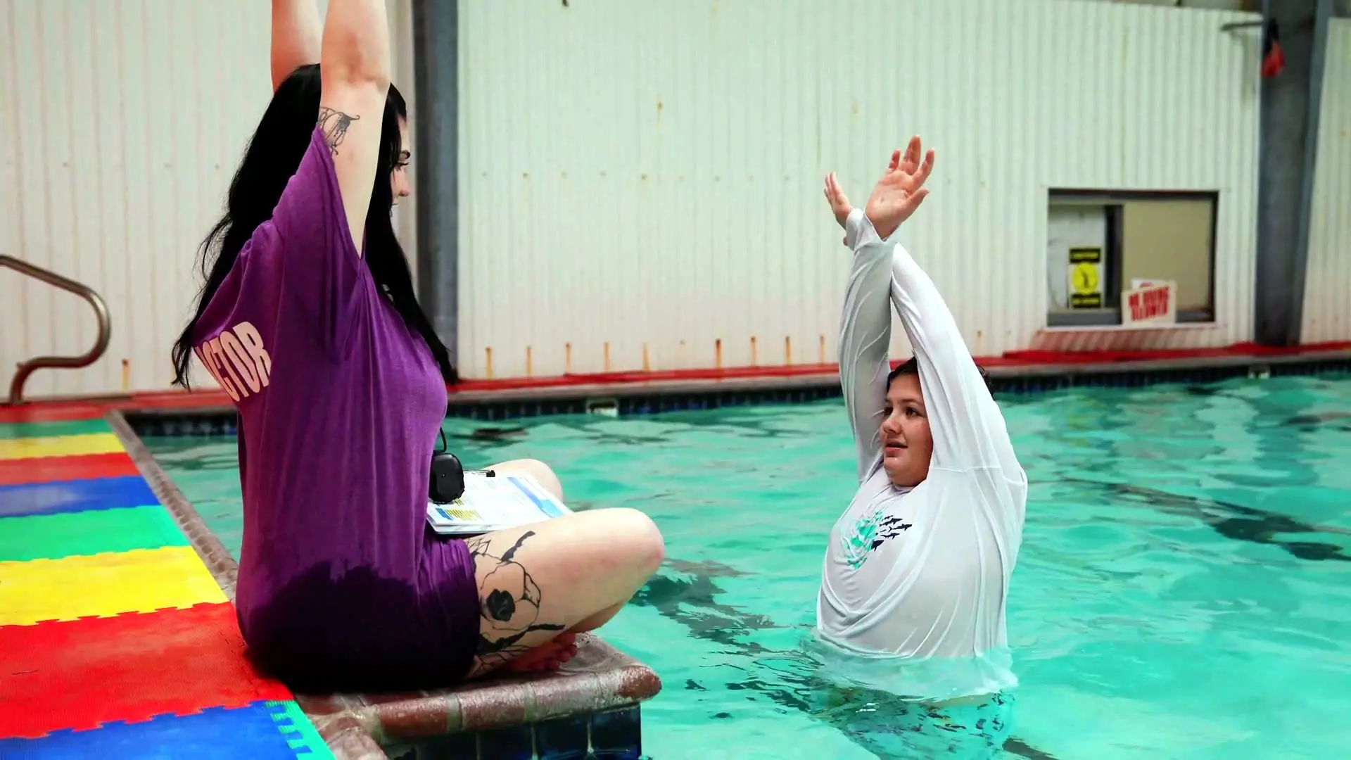 Swimsational's heated indoor pool: an instructor leads a stretch from the deck while a swimmer follows in the water
